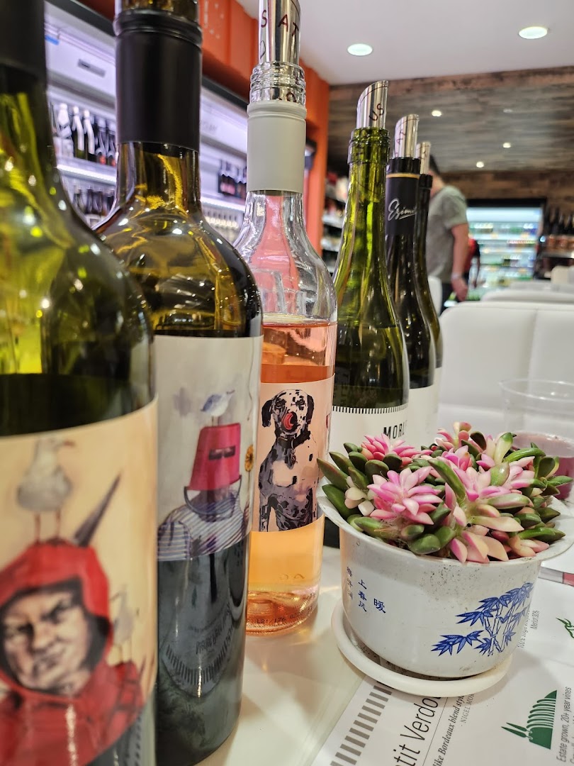 A close-up of various wine bottles with unique labels and a potted plant on a table inside Jays Bar.