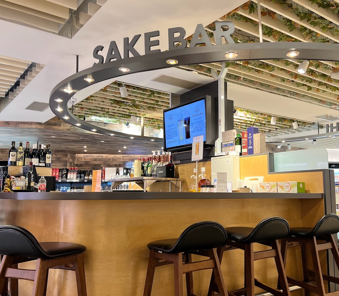 An inviting interior view of a modern sake bar with bar stools and a well-stocked counter.