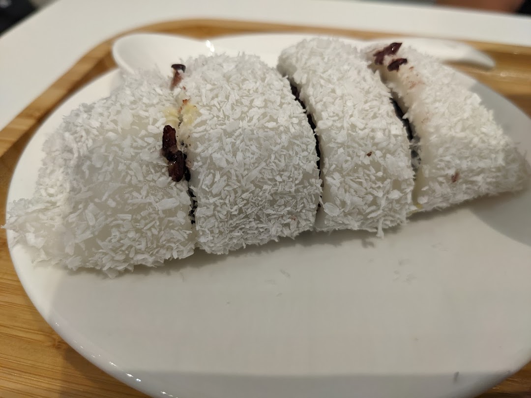 A plate of sliced white dessert covered in shredded coconut, revealing a dark filling.