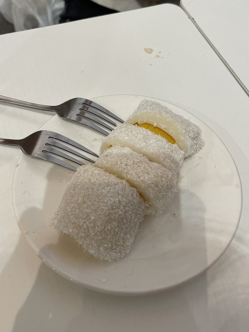 A plate of sliced coconut-dusted dessert with a yellow filling, served with two forks.