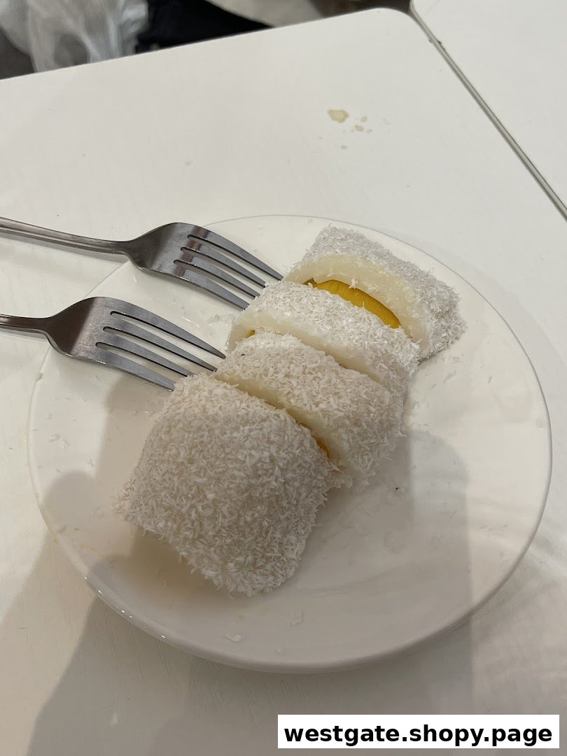 A plate of sliced coconut-dusted dessert with a yellow filling, served with two forks.