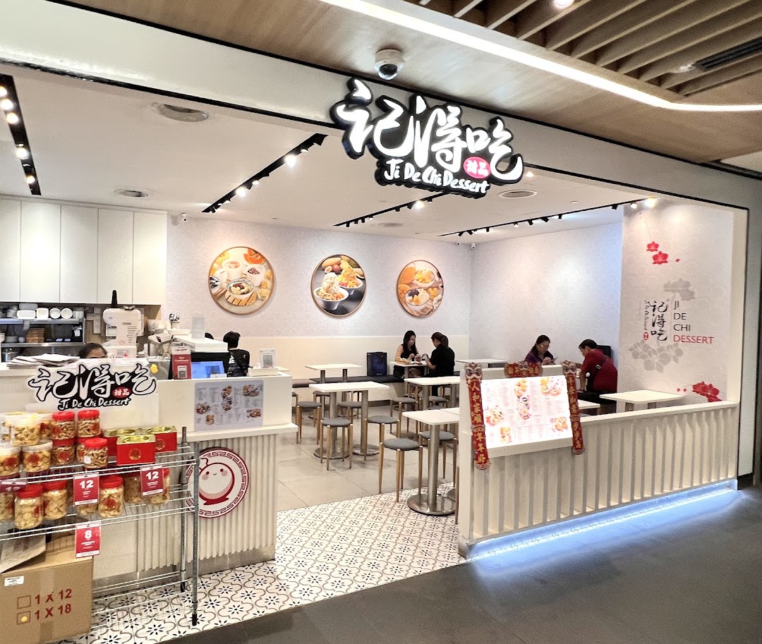The brightly lit entrance and interior of Ji De Chi Dessert, featuring seating and a display of products.