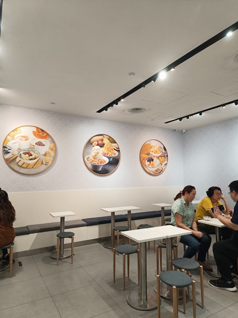 Interior view of Ji De Chi Dessert with customers enjoying treats and decorative food art on the walls.