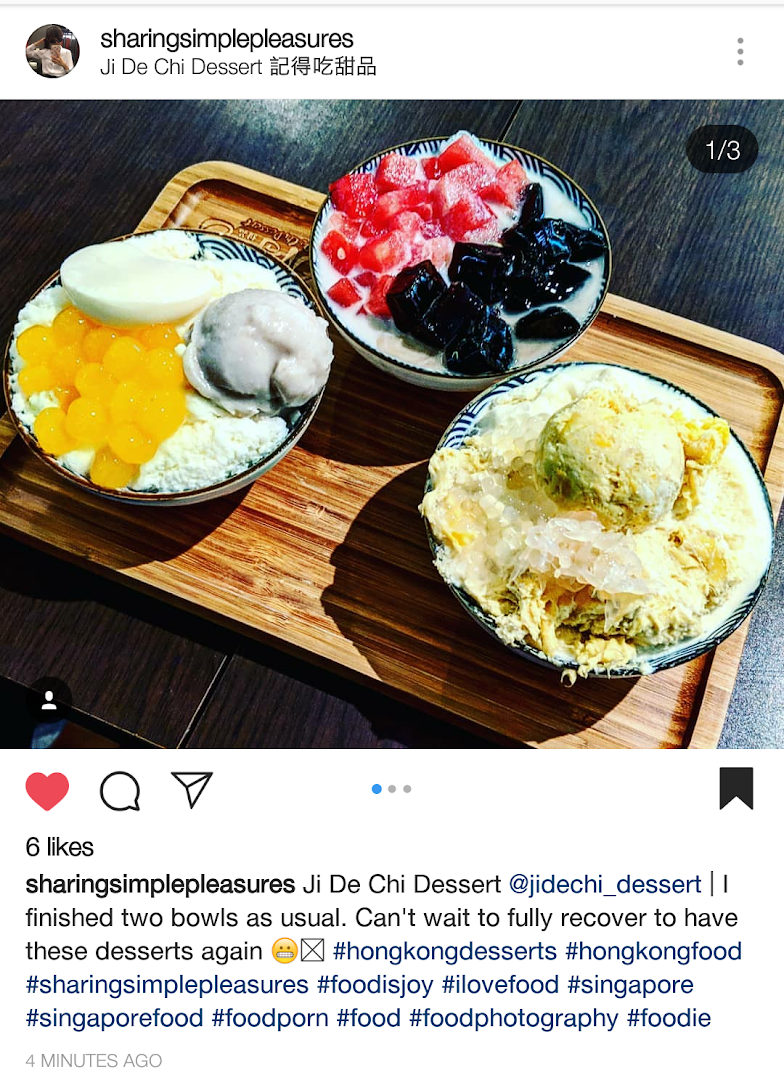 Three colorful dessert bowls with various toppings are presented on a wooden tray.
