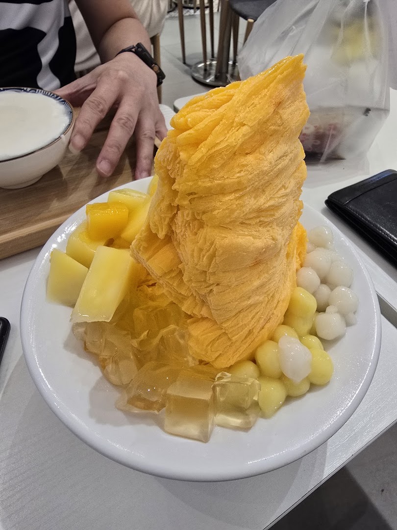A vibrant mango shaved ice dessert with fresh mango chunks, jelly, and chewy toppings.