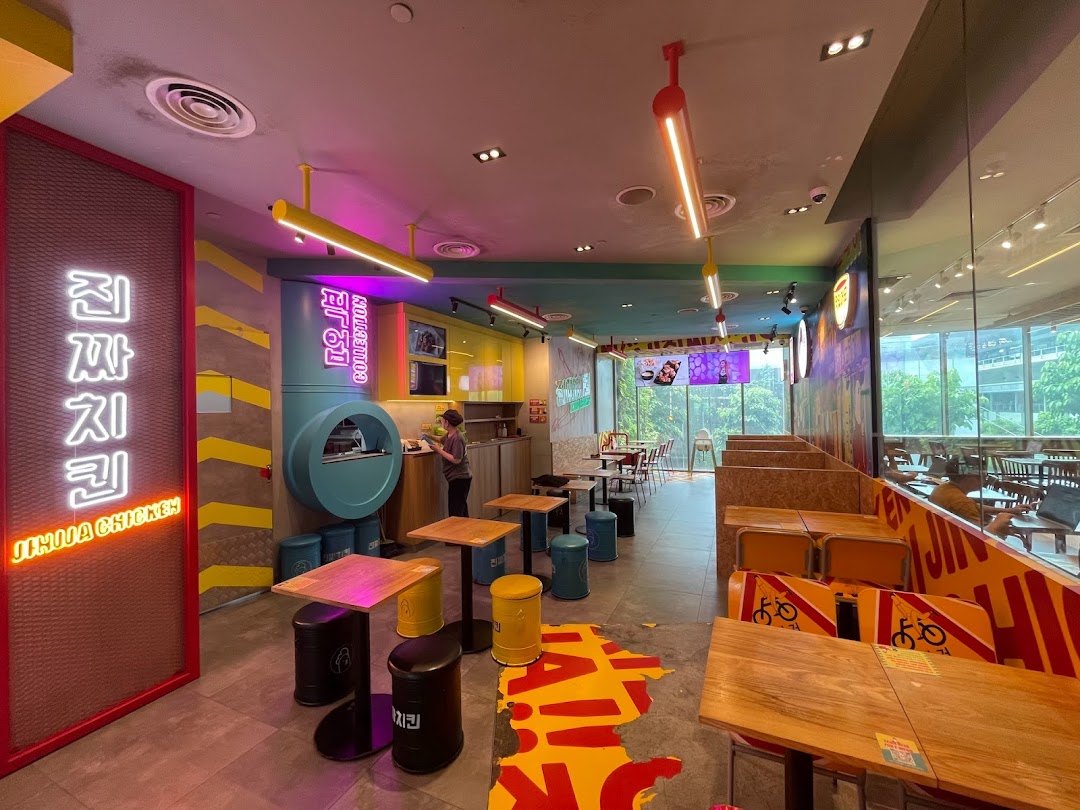 Vibrant interior of JINJJA Chicken with colorful decor, diverse seating, and a service counter.