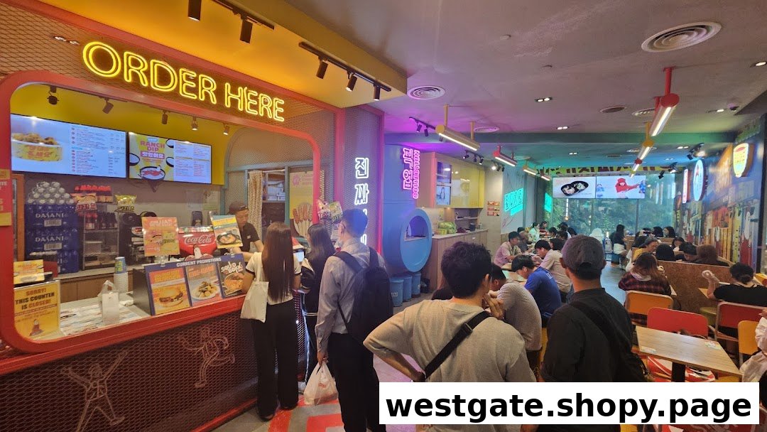 A vibrant interior shot of JINJJA Chicken, showing customers at the ordering counter and dining area.