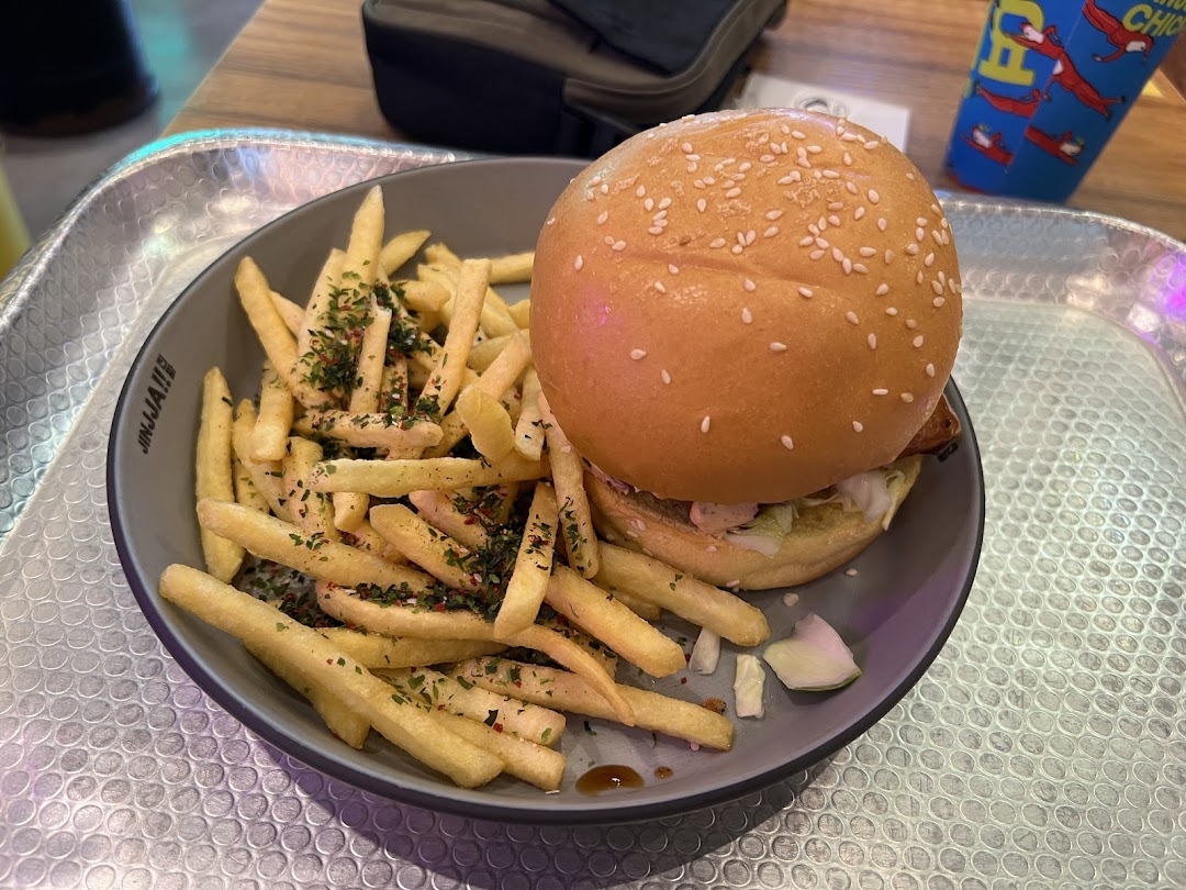 A delicious burger and seasoned fries served on a plate at JINJJA Chicken.