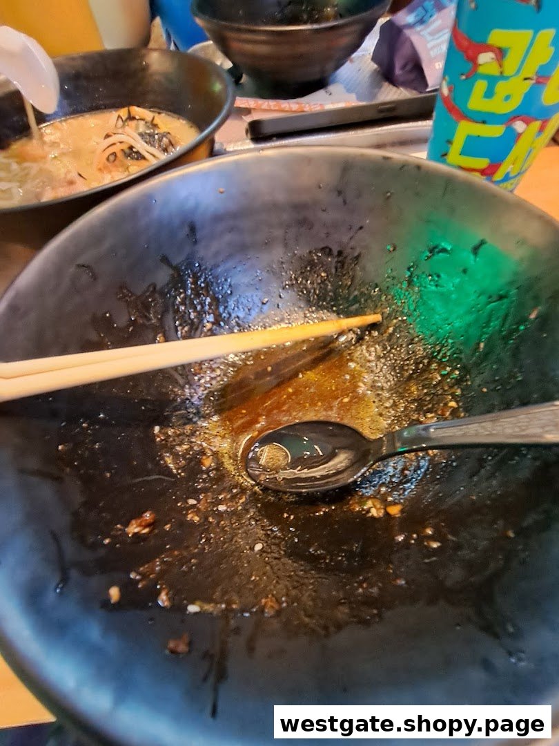 An empty ramen bowl with chopsticks and spoon, showing remnants of a delicious meal.