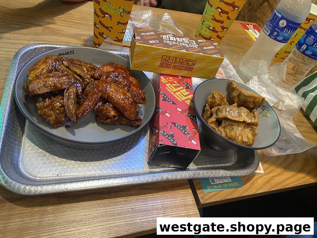 A delicious spread of JINJJA Chicken's Korean fried chicken wings, dumplings, and a corn dog on a table.