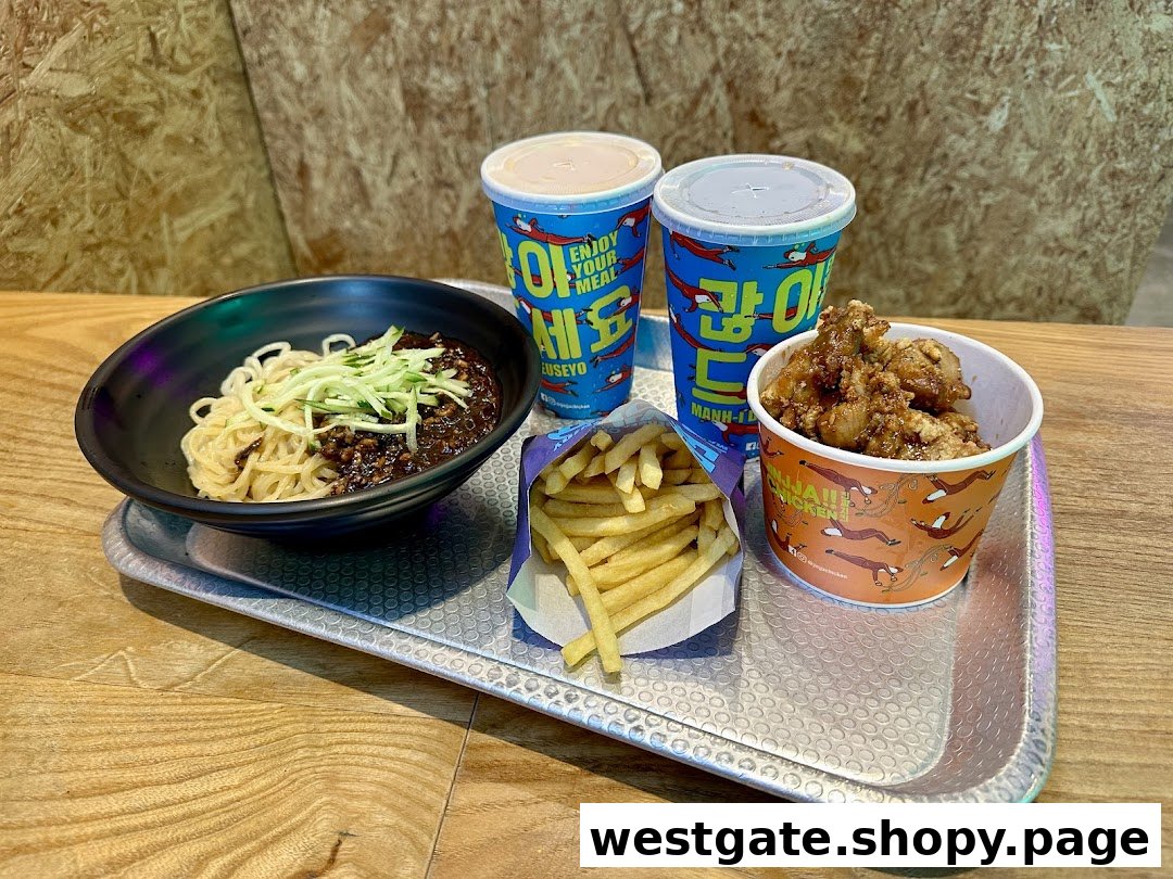 A tray with Korean black bean noodles, fried chicken, french fries, and two drinks.