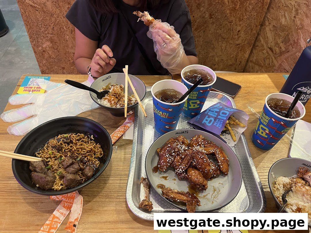 A table at JINJJA Chicken featuring Korean fried chicken, noodles, rice bowls, and drinks.