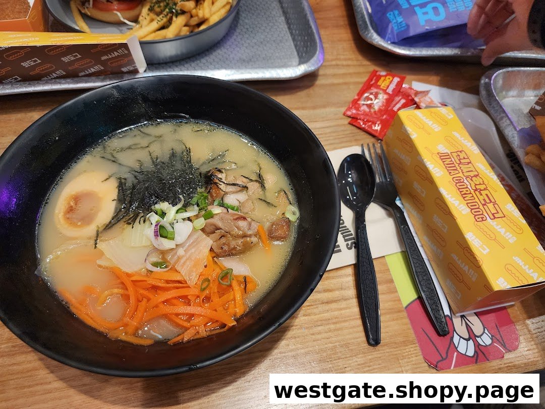 A close-up of a delicious ramen bowl with egg, chicken, and vegetables, alongside a JINJJA Corndog box.