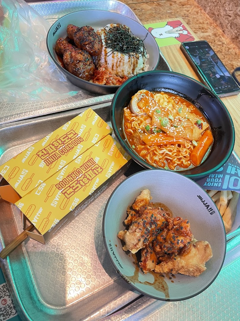 A delicious spread of Korean fried chicken, ramen, rice, and corn dogs from JINJJA Chicken.