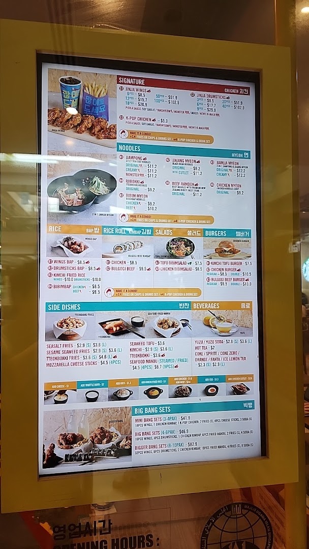 A digital menu board displaying various Korean fried chicken, noodle, rice, and burger dishes.