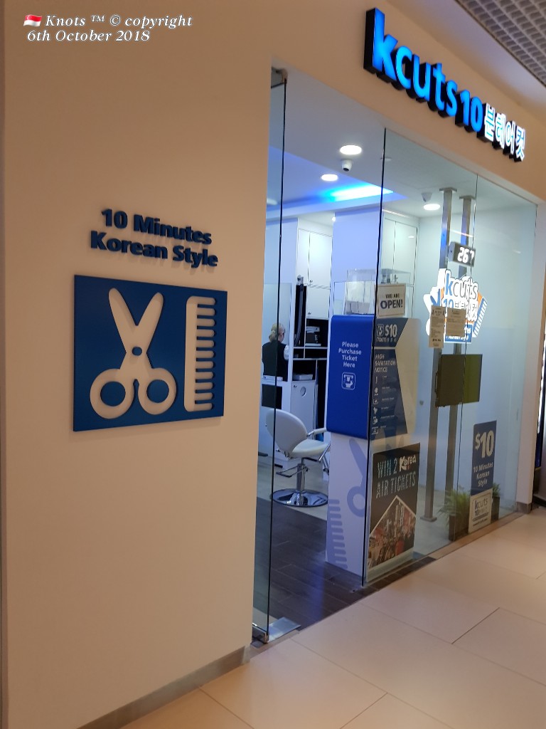 The entrance of kcuts 10, a hair salon, featuring its logo, '10 Minutes Korean Style' sign, and glass doors.