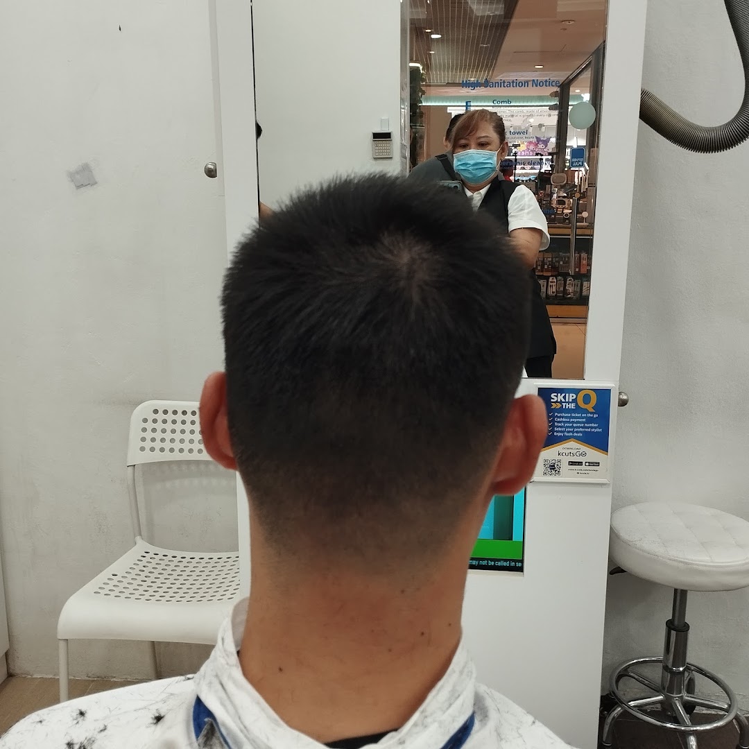 A customer receives a haircut at kcuts, with the stylist reflected in the mirror.