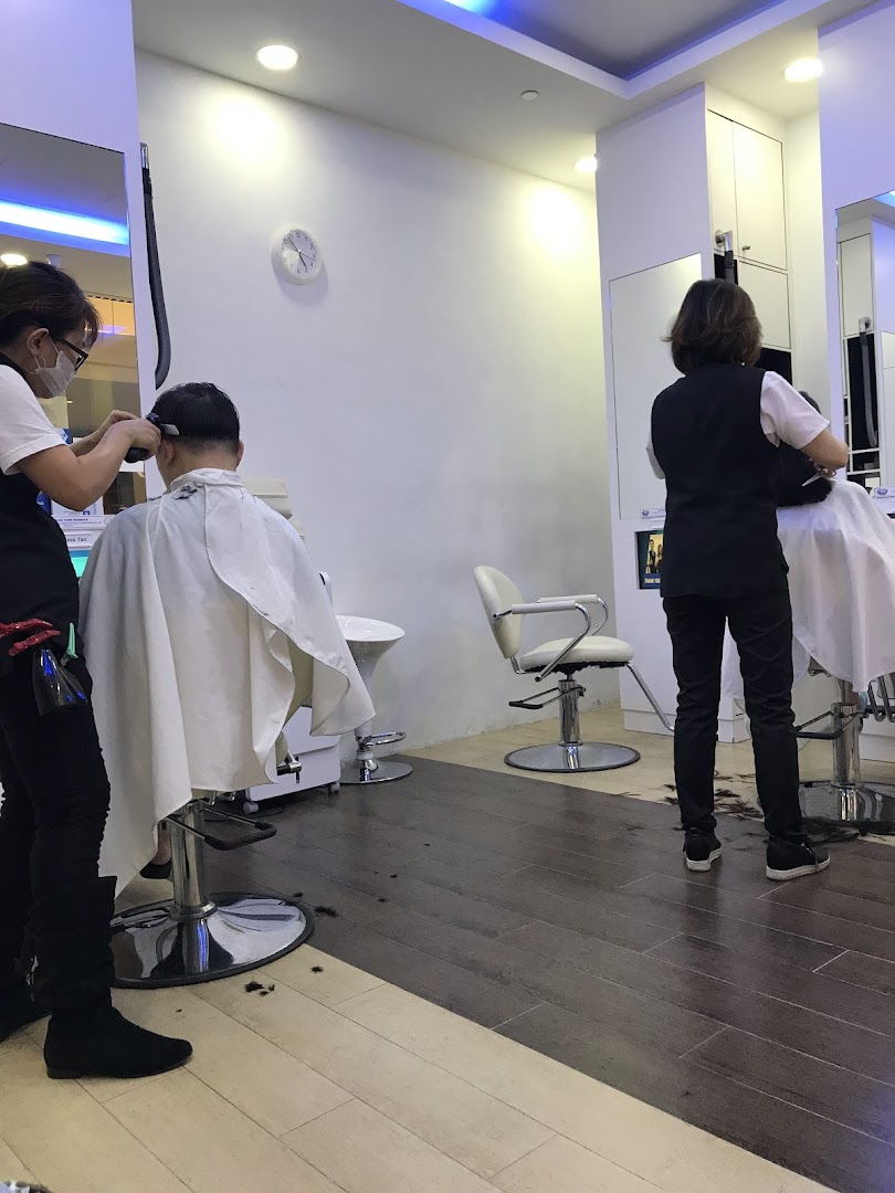 Two customers receiving haircuts from stylists inside a modern kcuts salon.