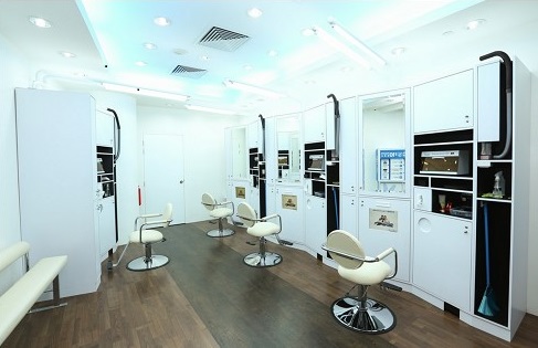Clean, modern interior of kcuts salon with multiple white styling stations and chairs.