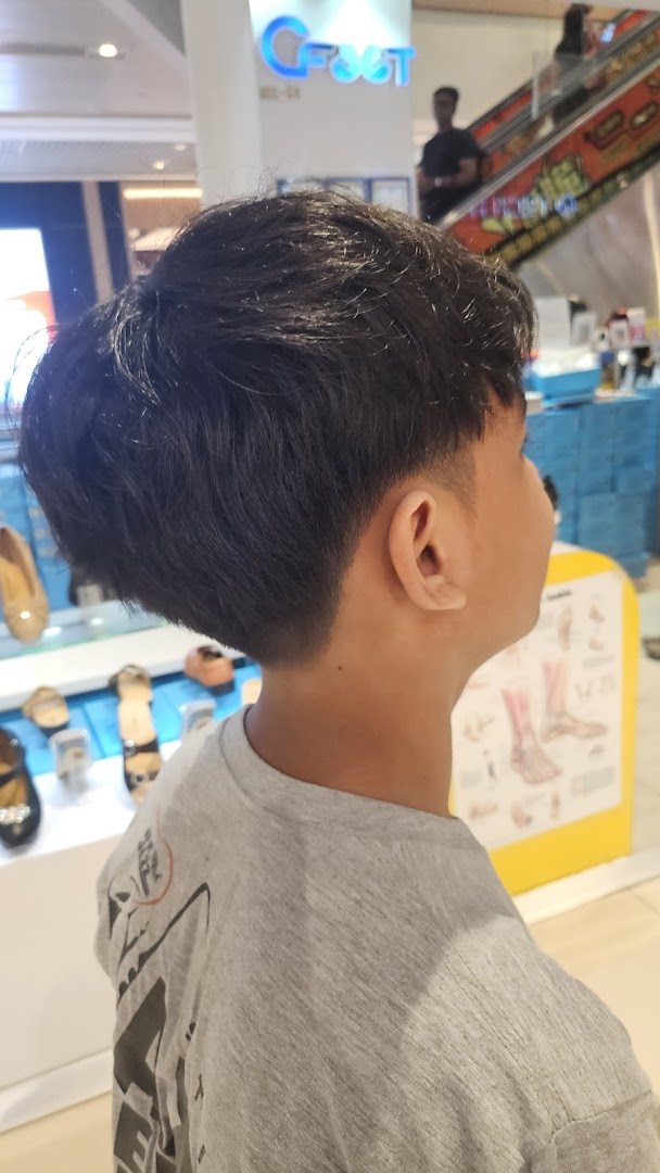 A person with a fresh haircut, seen from behind, inside a mall.