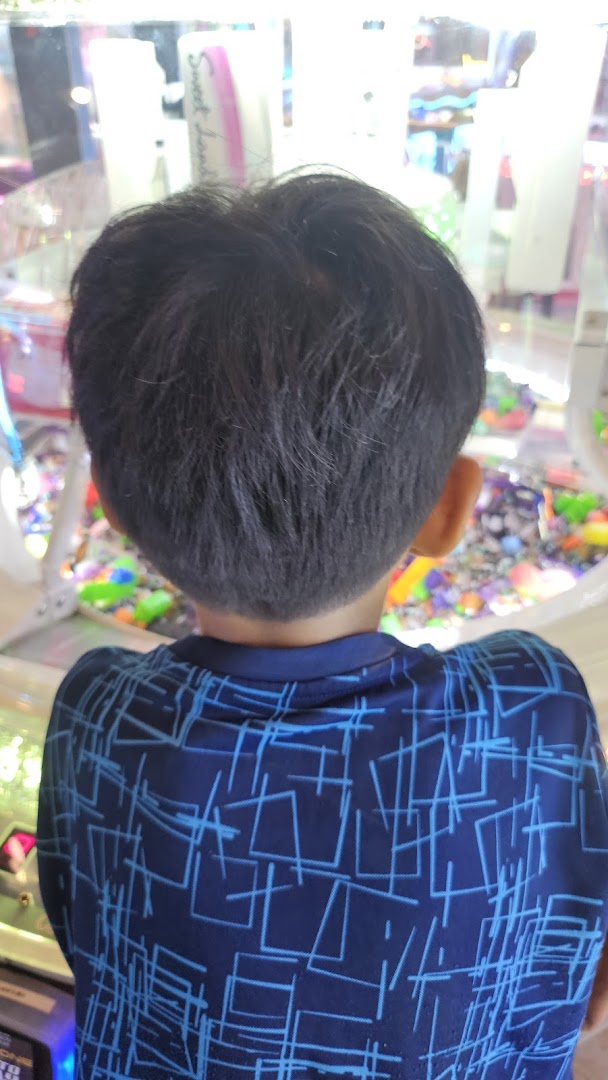 A child's back view, looking intently into an arcade game machine.