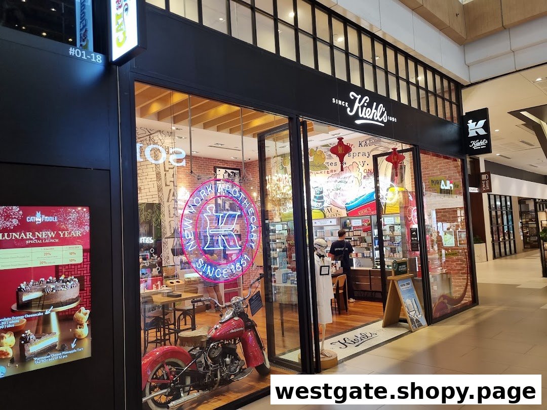 The storefront of Kiehl's Westgate, featuring a vintage motorcycle, neon sign, and product displays.