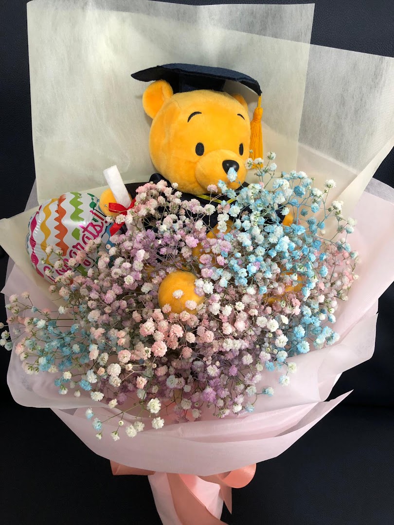 A vibrant graduation bouquet featuring a Winnie the Pooh plush, colorful baby's breath, and a 'Congrats!' balloon.