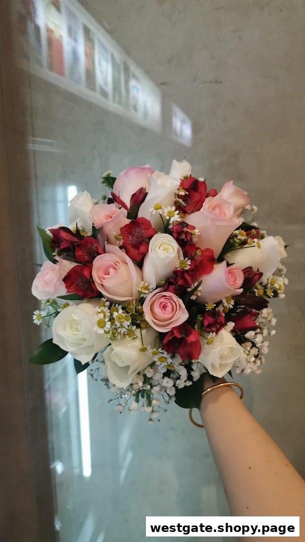 A hand holds a vibrant bouquet of pink, white, and red roses with delicate filler flowers.