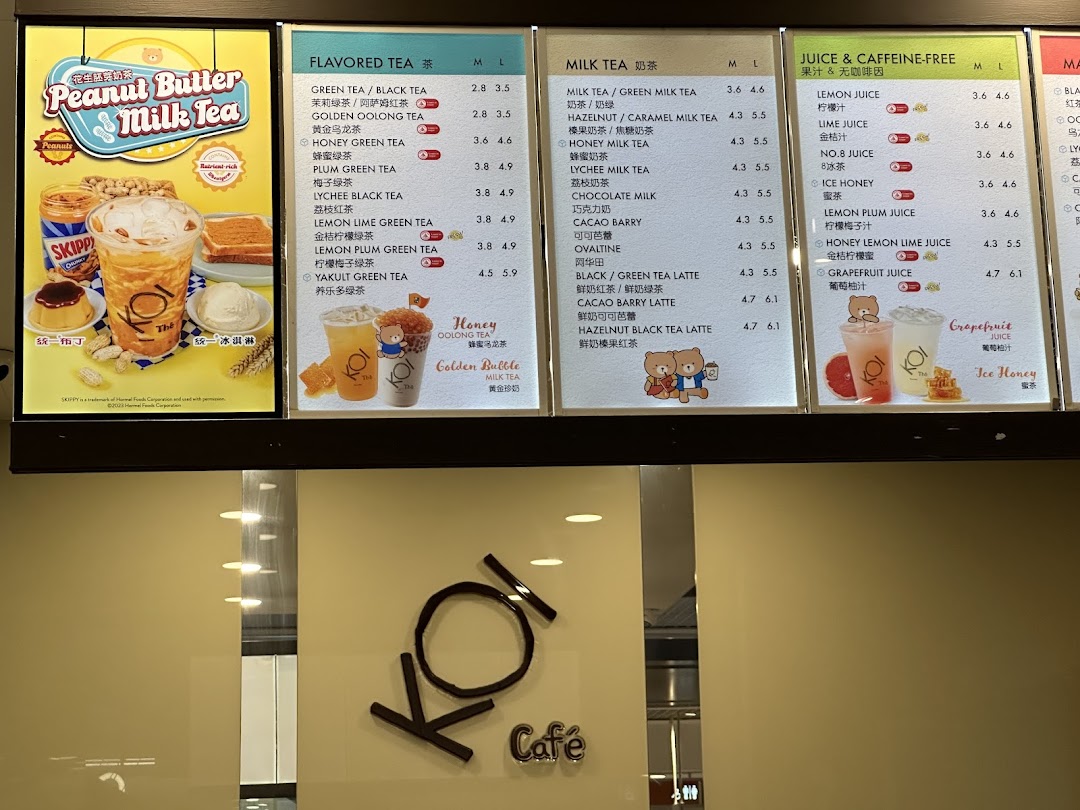 A brightly lit menu board at KOI Thé, showcasing various tea, milk tea, and juice options.
