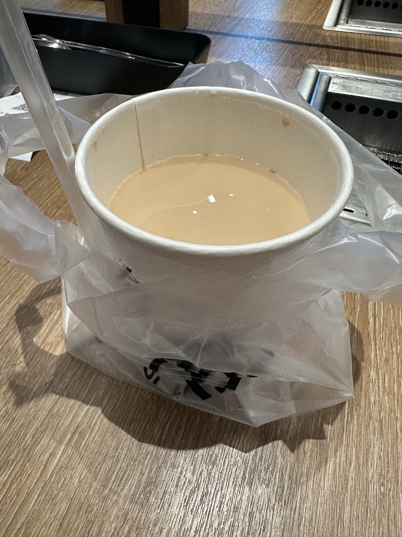 A cup of bubble tea in a plastic bag with a straw, placed on a wooden table.