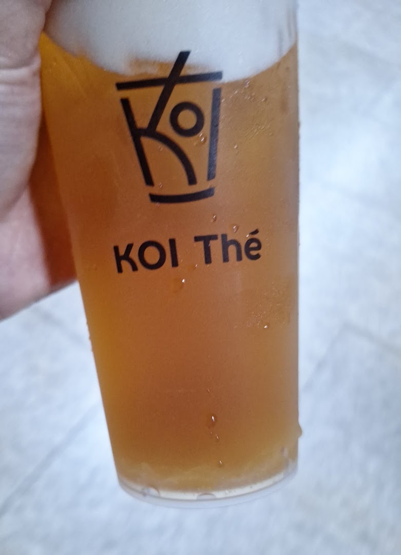 A close-up of a refreshing KOI Thé beverage in a branded cup with foam.