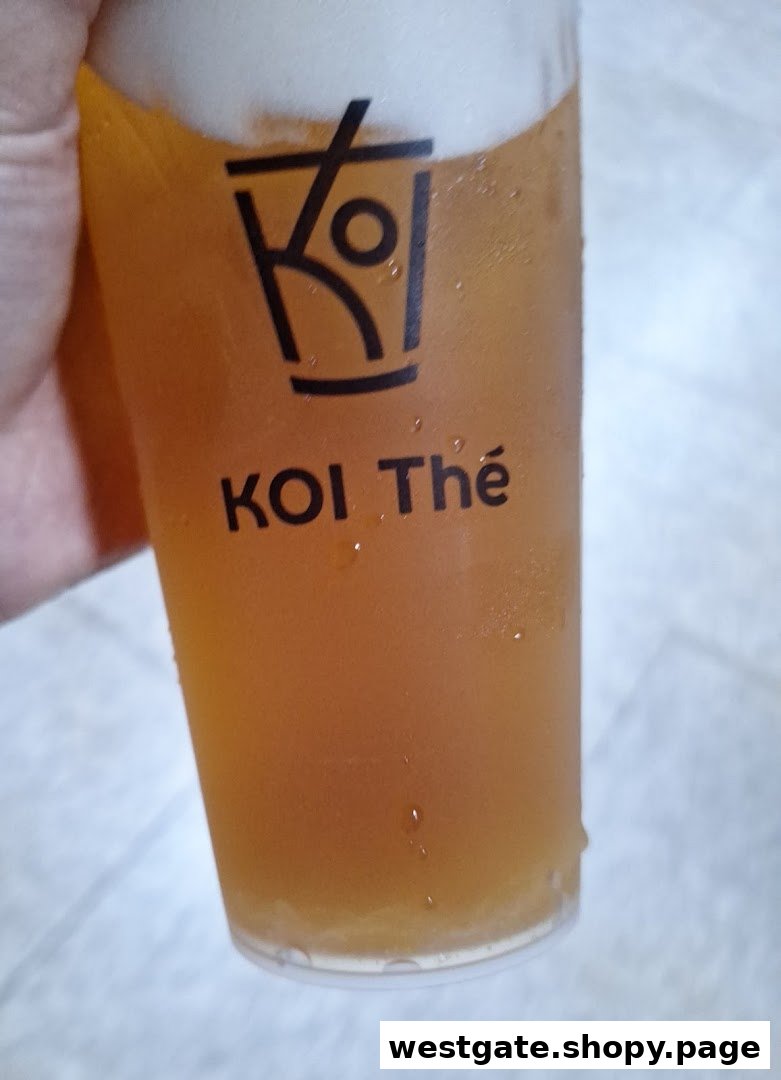 A close-up of a refreshing KOI Thé beverage in a branded cup with foam.