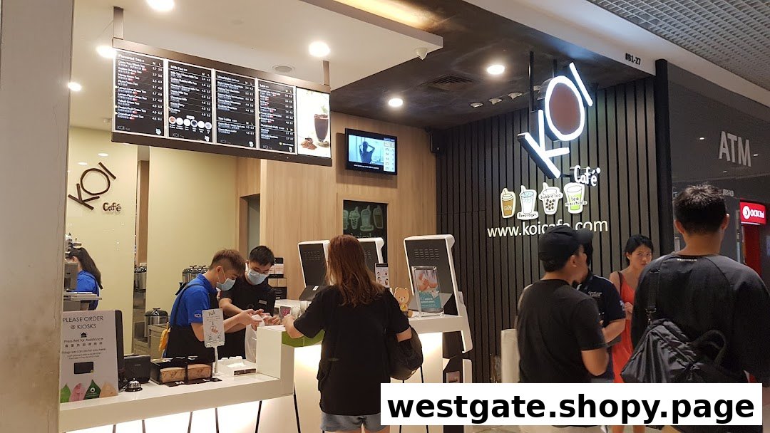 Customers order at the bustling counter of KOI Thé, featuring staff, self-service kiosks, and menu boards.