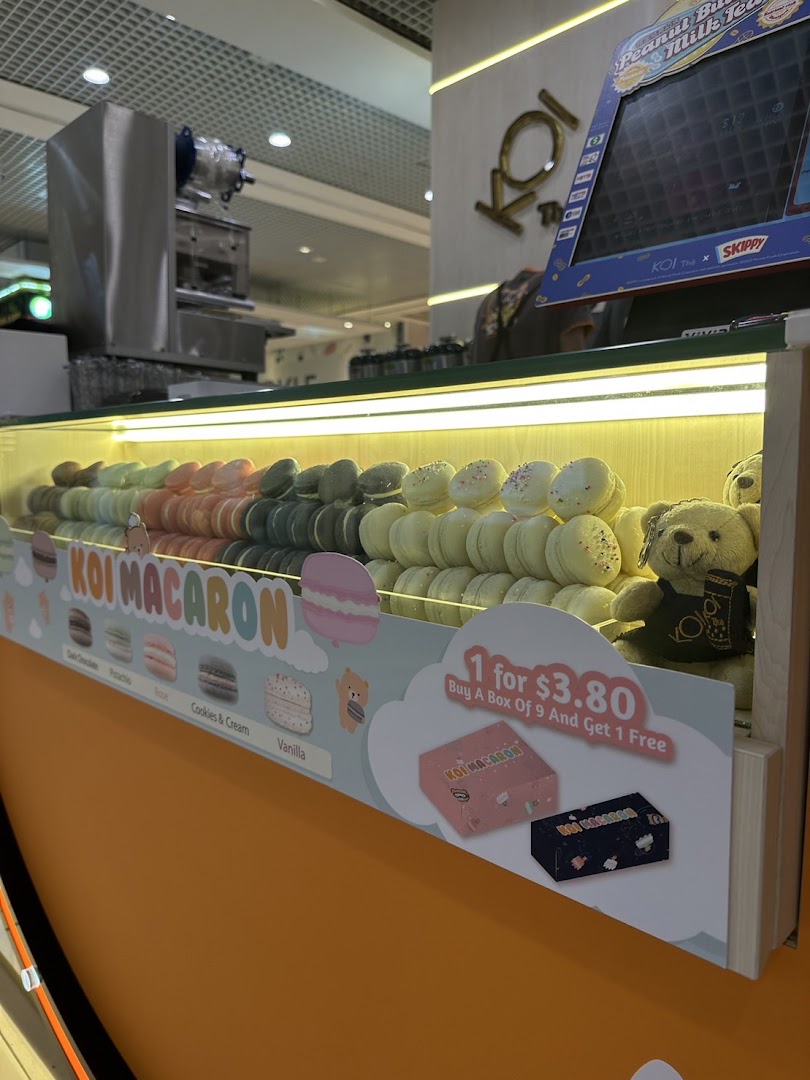 A vibrant display of colorful macarons with a promotional offer at KOI Thé.