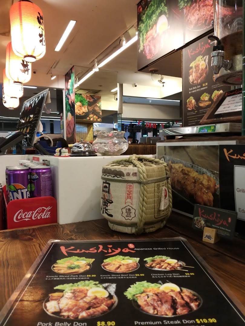 A close-up view of Kushiya Japanese Grill House's counter, featuring a menu, Japanese decor, and beverages.