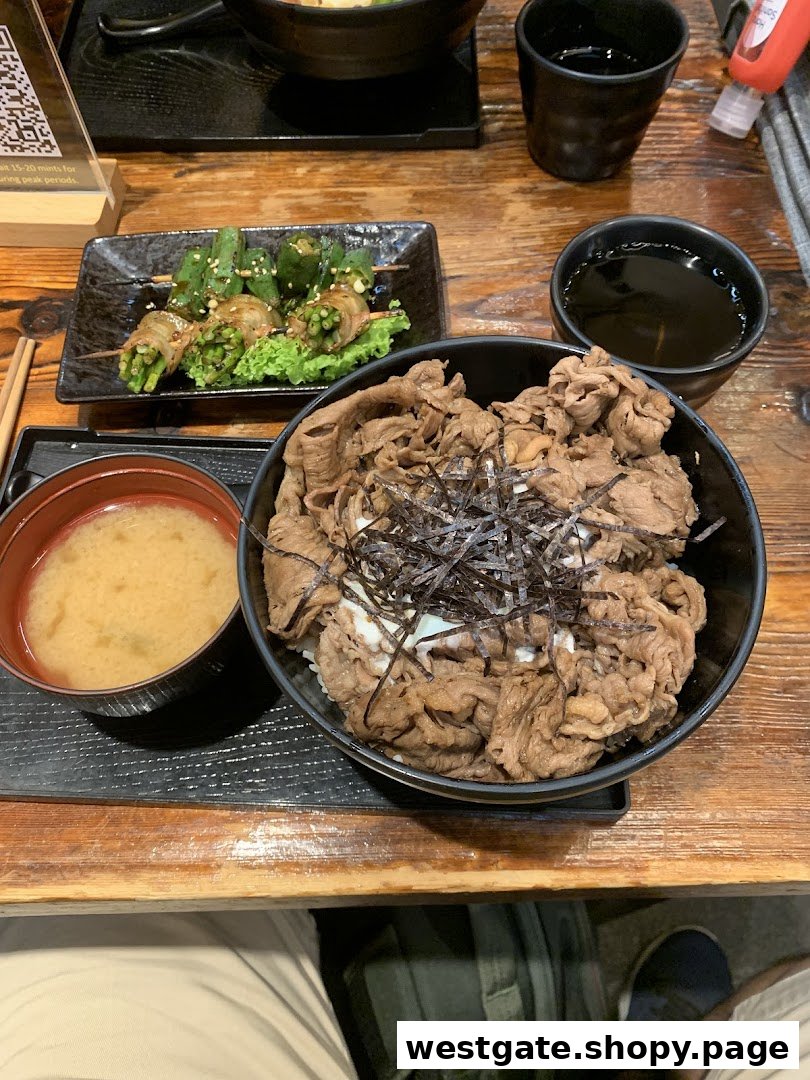 A delicious Japanese beef bowl (Gyudon) set with miso soup and grilled vegetable skewers on a wooden table.