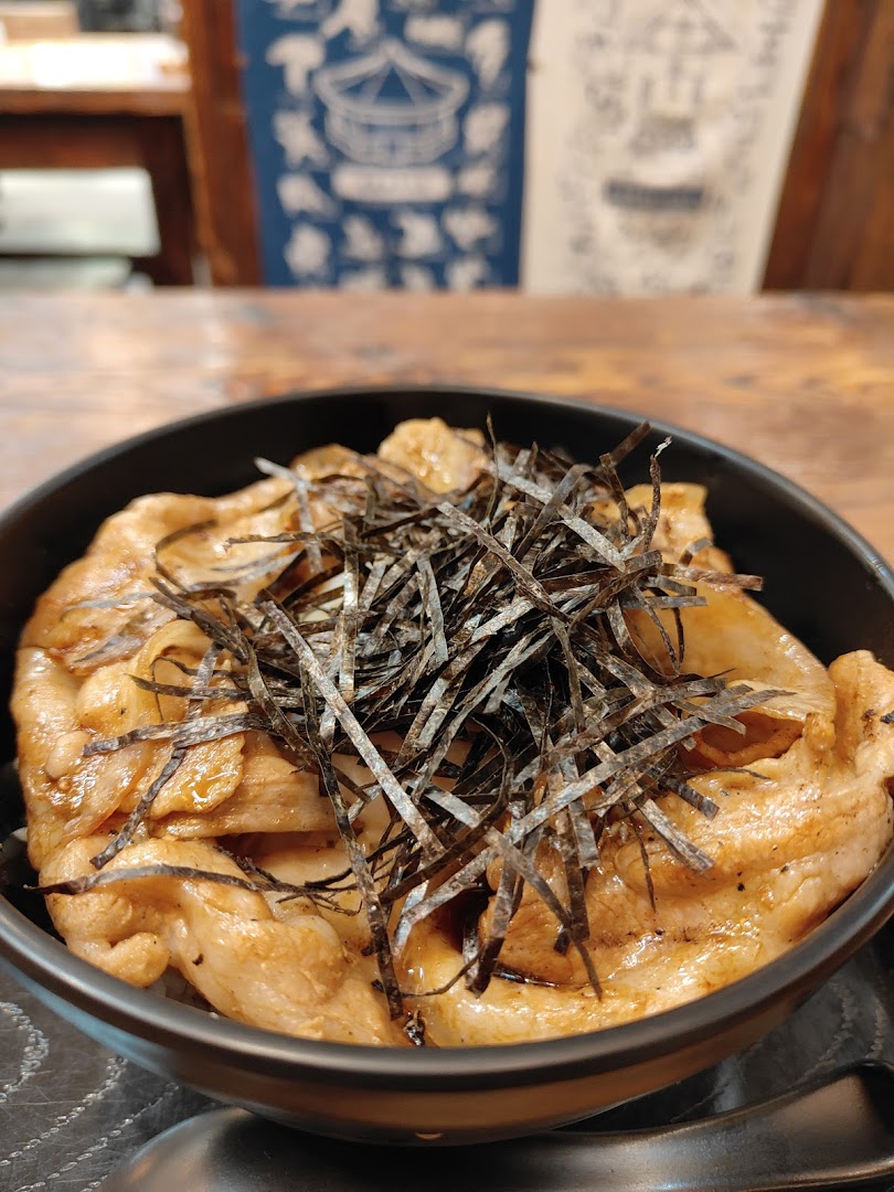 A close-up of a delicious Japanese grilled pork donburi bowl topped with shredded nori seaweed.
