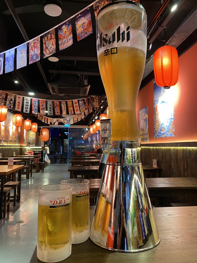 A large Asahi beer tower and two frosty glasses on a table inside a Japanese grill house.