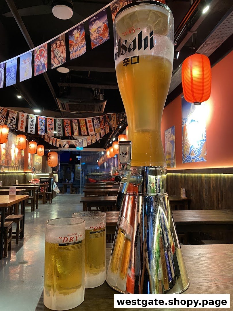 A large Asahi beer tower and two frosty glasses on a table inside a Japanese grill house.