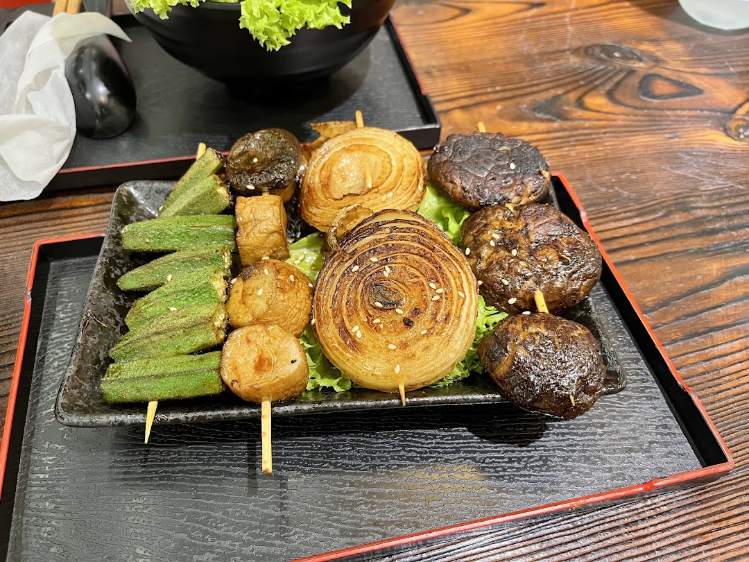 A plate of assorted grilled vegetables on skewers, including okra, mushrooms, and onions, from Kushiya Japanese Grill House.