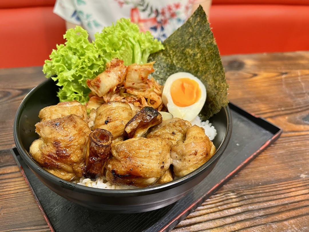 A delicious Japanese donburi bowl featuring grilled chicken, kimchi, a soft-boiled egg, and fresh lettuce.