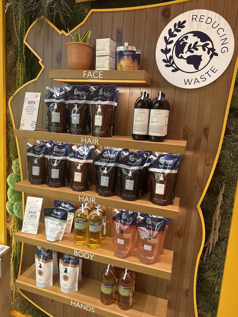 A L'Occitane display showcasing eco-refill products for face, hair, body, and hands, promoting waste reduction.