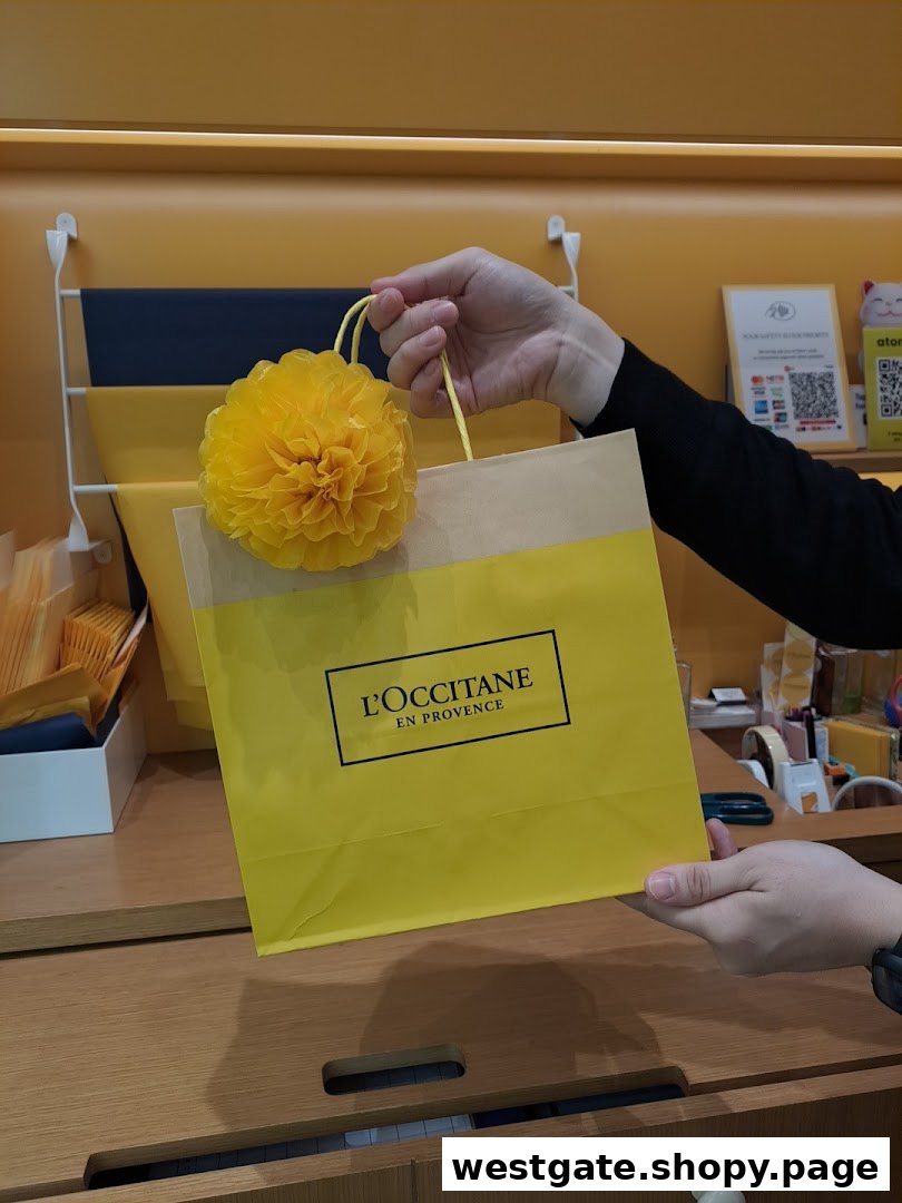 A person holds a vibrant yellow L'OCCITANE shopping bag adorned with a decorative flower.