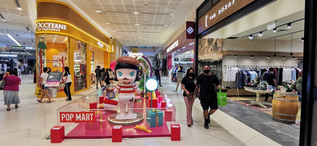A bustling mall corridor featuring L'OCCITANE, other retail shops, and a vibrant Pop Mart display.