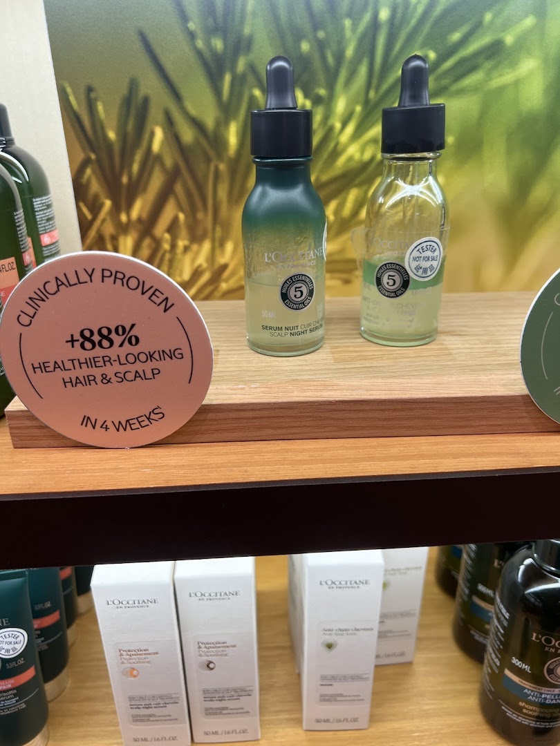 Close-up of L'Occitane hair and scalp care products on display, featuring a night serum and clinical results.