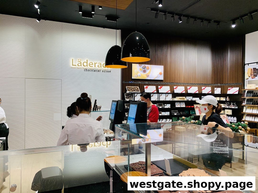Interior view of Läderach chocolate shop with staff, display counter, and branded products.