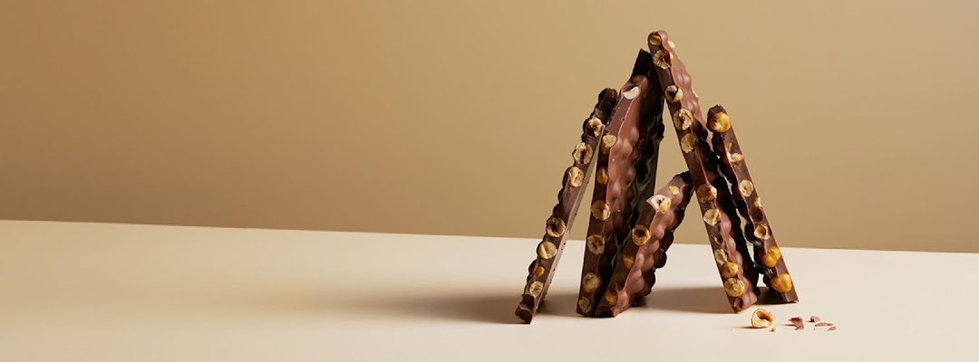Artfully arranged chocolate bars with whole hazelnuts on a minimalist background.