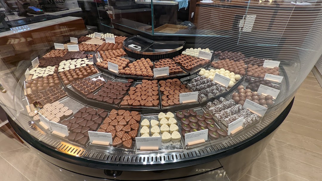 A vibrant display of assorted gourmet chocolates and pralines in a circular glass case.