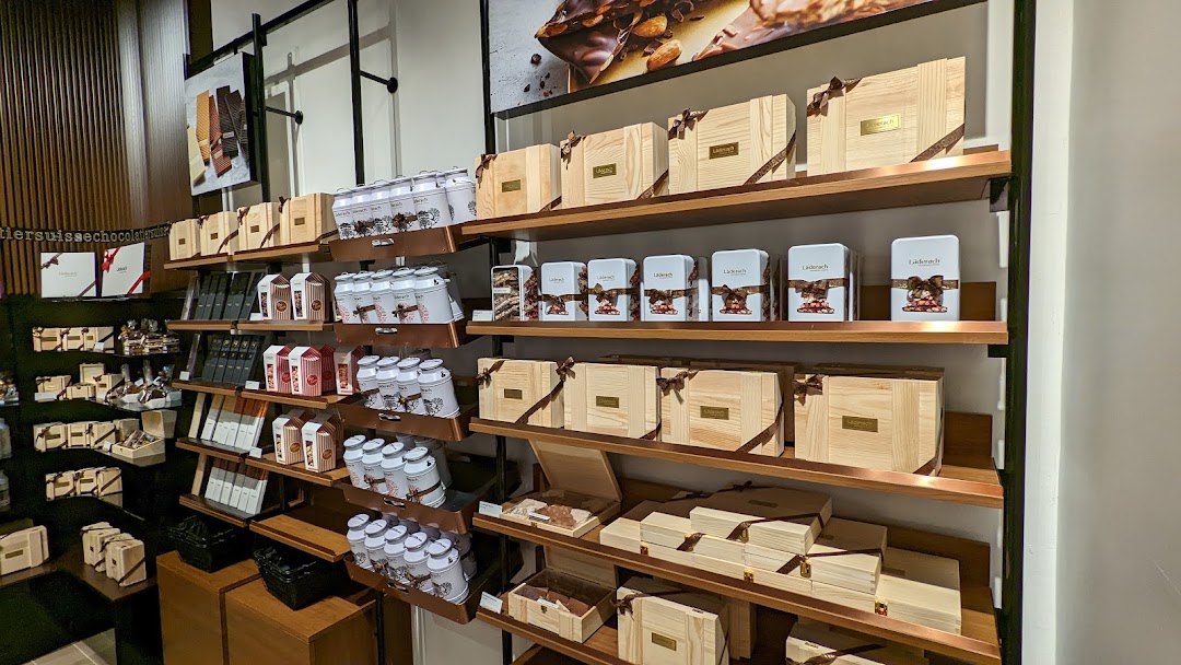 An interior view of Läderach chocolate shop, showcasing shelves filled with various chocolate products and gift boxes.