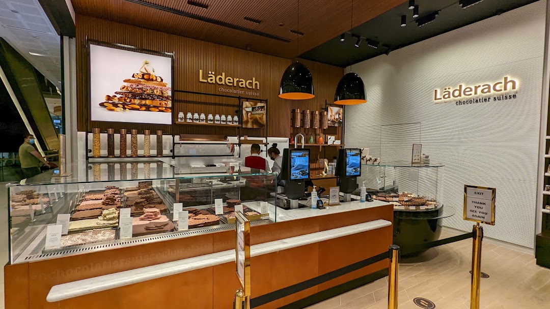 Interior view of Läderach chocolate shop, showcasing fresh chocolate displays and a welcoming counter area.